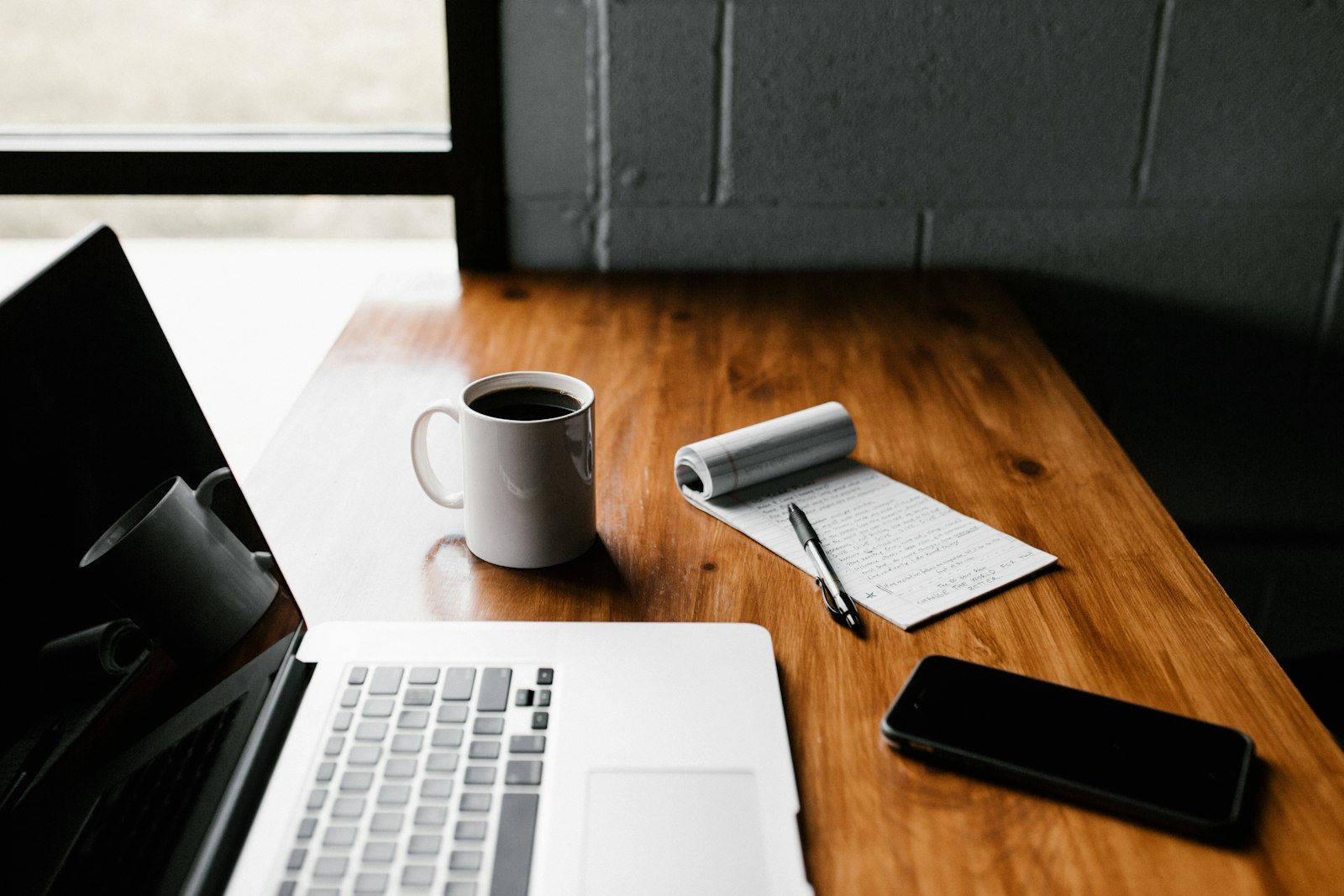 A calm laptop workspace with a notebook and coffee